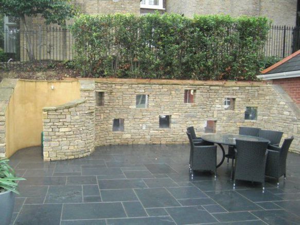 Large sloping garden design in Kenley, Surrey with stone faced retaining walls and curved cooking area..