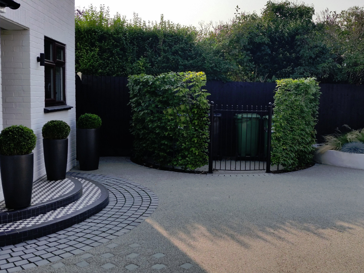 Front garden design in Woking Surrey with resin drivewayhire with feature wall around courtyard.