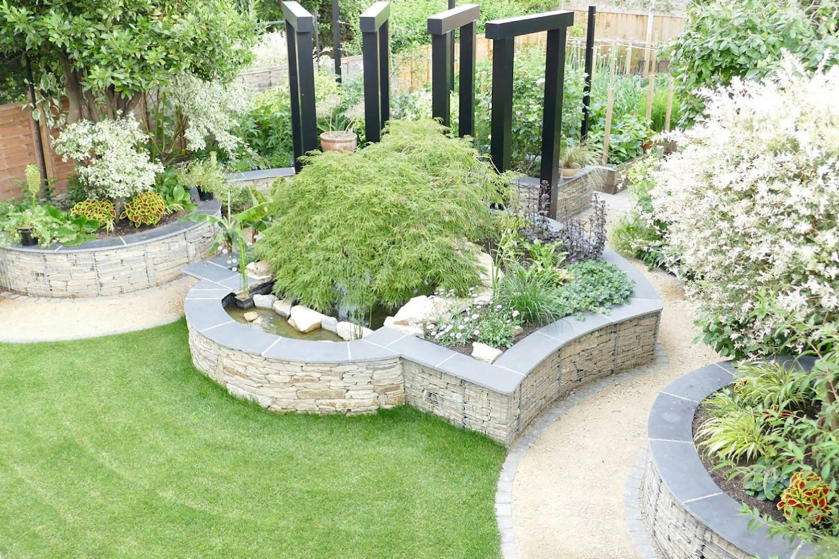 Garden design in St Albans, Hertfordshire with gabion retaining walls, steel pergola, and vegetable area.